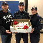 Photo of members in Hamilton holding a cake with the words "enough is enough #burntbyphoenix"